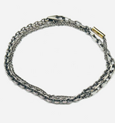 bracelet is comprised of three separate chains including a thin double strand cable chain, more dense single strand cable chain and an anchor chain, accented by an 18k yellow gold tube