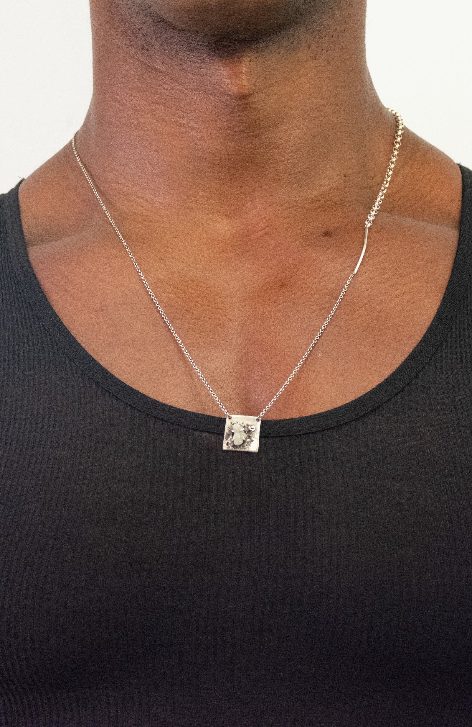 a black raw diamond is secured on this sterling pendant hanging from a beaded ball chain that is disrupted by a 1" bar