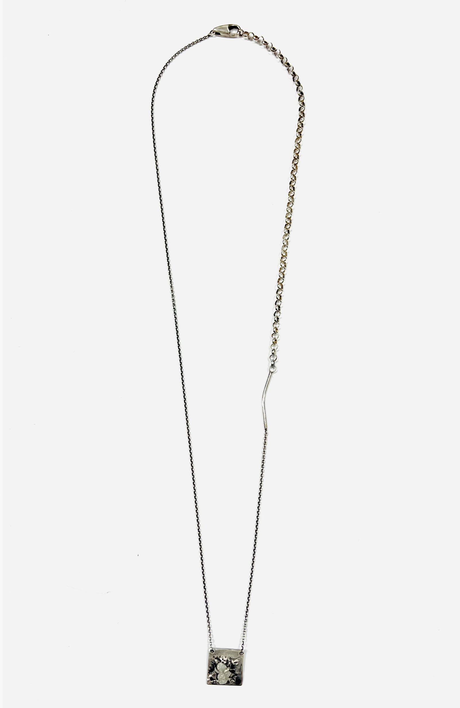 a black raw diamond is secured on this sterling pendant hanging from a beaded ball chain that is disrupted by a 1" bar