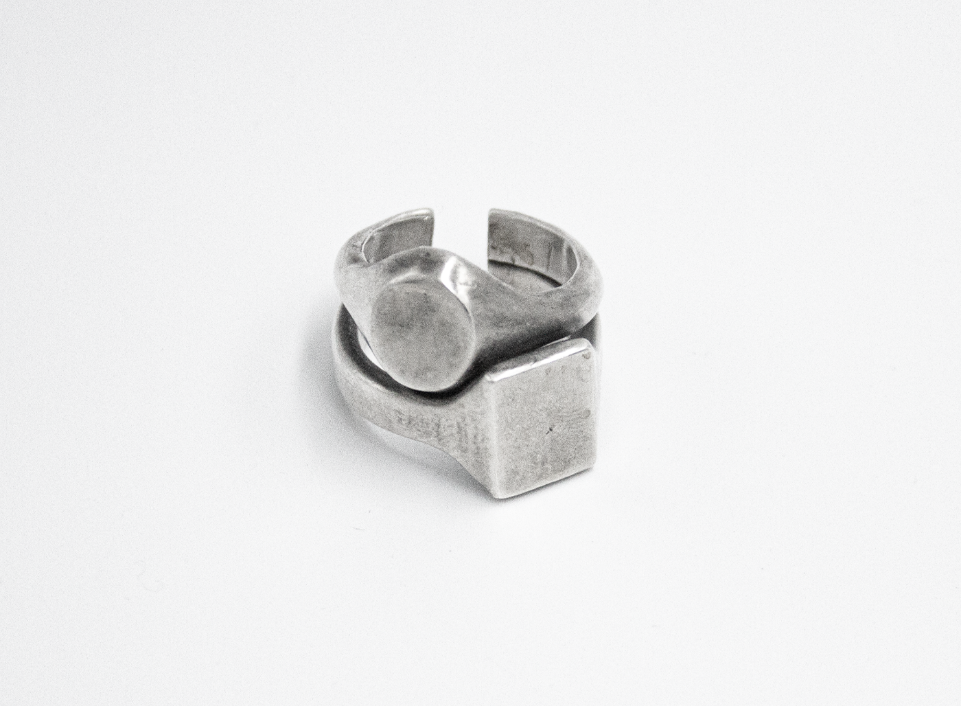 stacked open ring is made from reclaimed silver and features large circular and square signets that hug one another