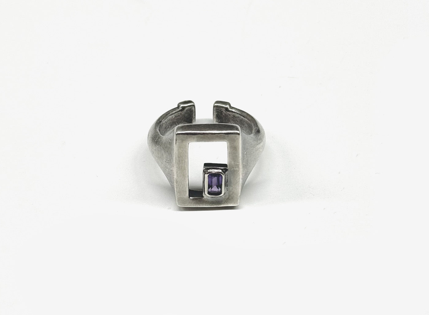 a single emerald-cut amethyst gemstone sits elegantly framed in the corner of an open face sterling silver signet ring that distressed and hand finished