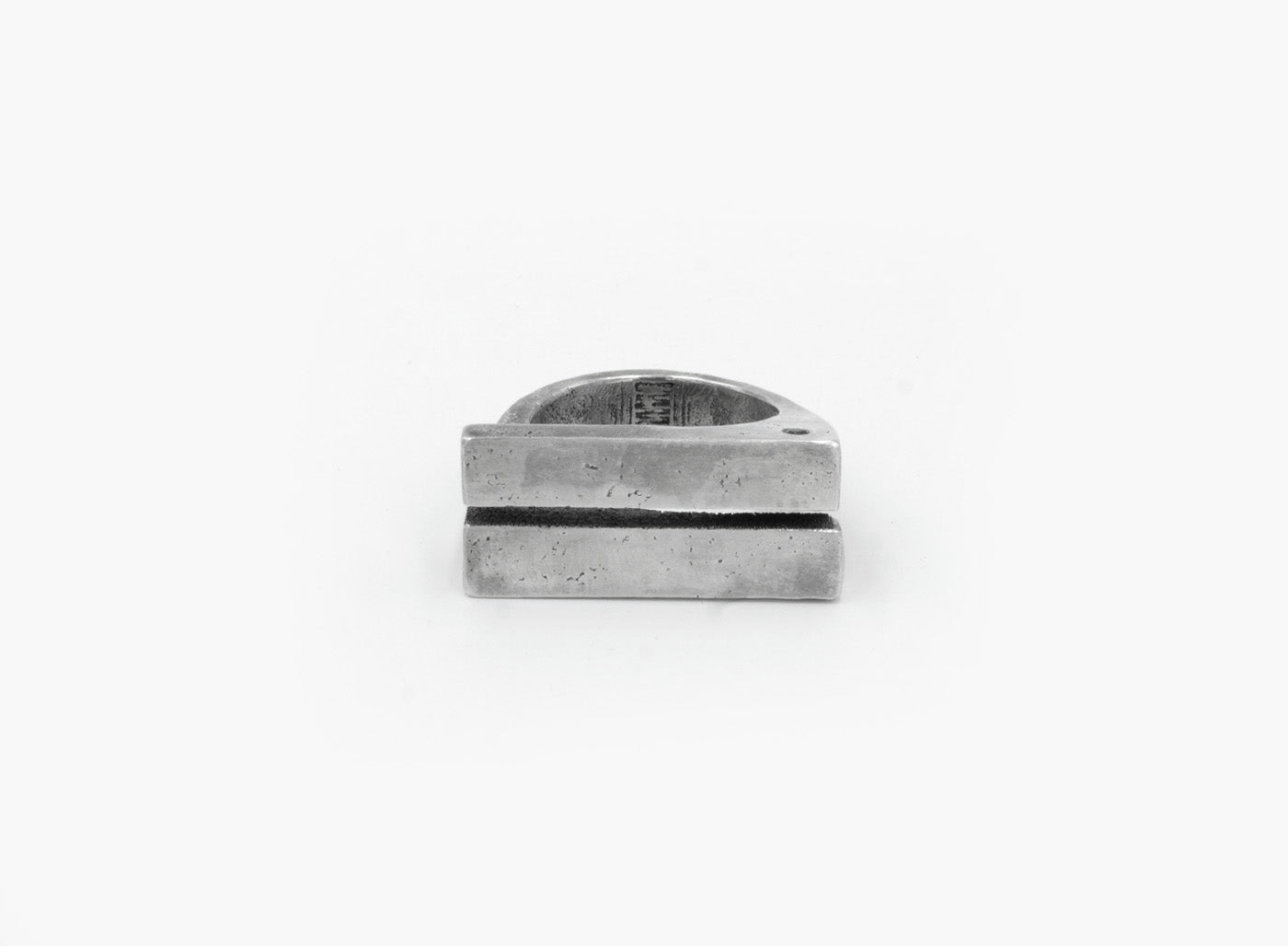 this distressed double bar ring features two wide, parallel sterling silver bands connected by a ruby accent. its rugged, hand-forged texture enhances the raw, sculptural feel of the design