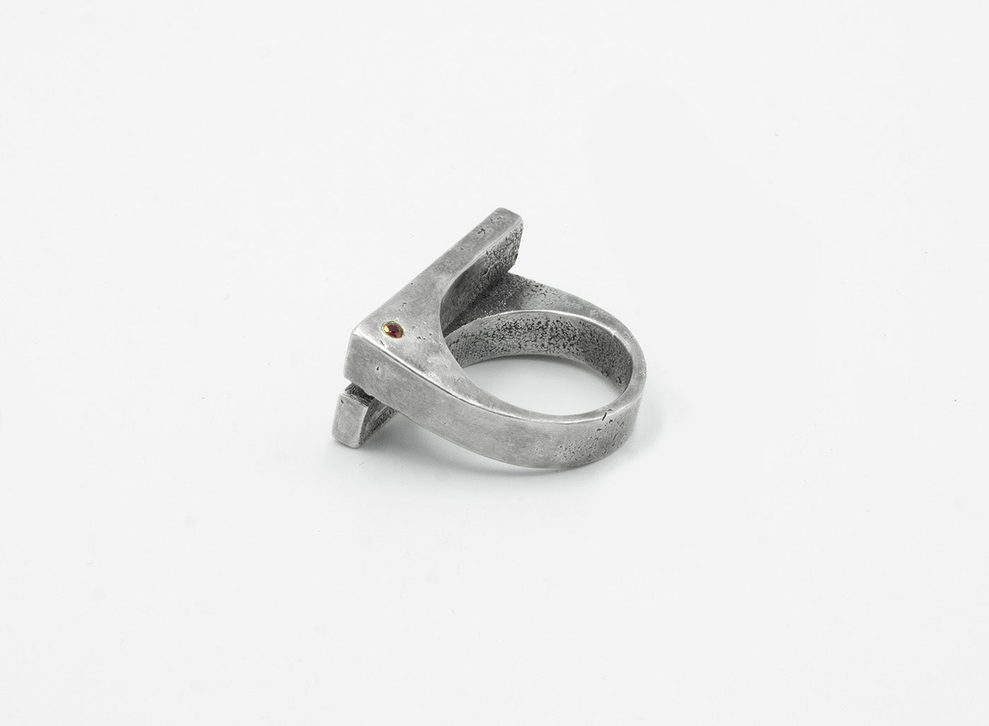 this distressed double bar ring features two wide, parallel sterling silver bands connected by a ruby accent. its rugged, hand-forged texture enhances the raw, sculptural feel of the design