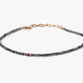 adjustable black diamond bracelet is finished with an 18k gold anchor chain and a single ruby