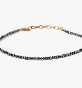 adjustable black diamond bracelet is finished with an 18k gold anchor chain and a single ruby