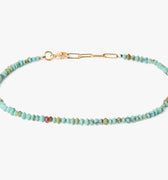 a strand of turquoise stones are accented by a single ruby and finished with 18k yellow gold links